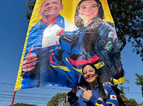 Manu Bim posa para foto com bandeira que mostra o pai