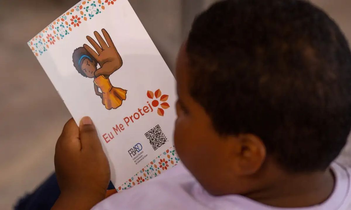 Criança segura folheto sobre o maio laranja