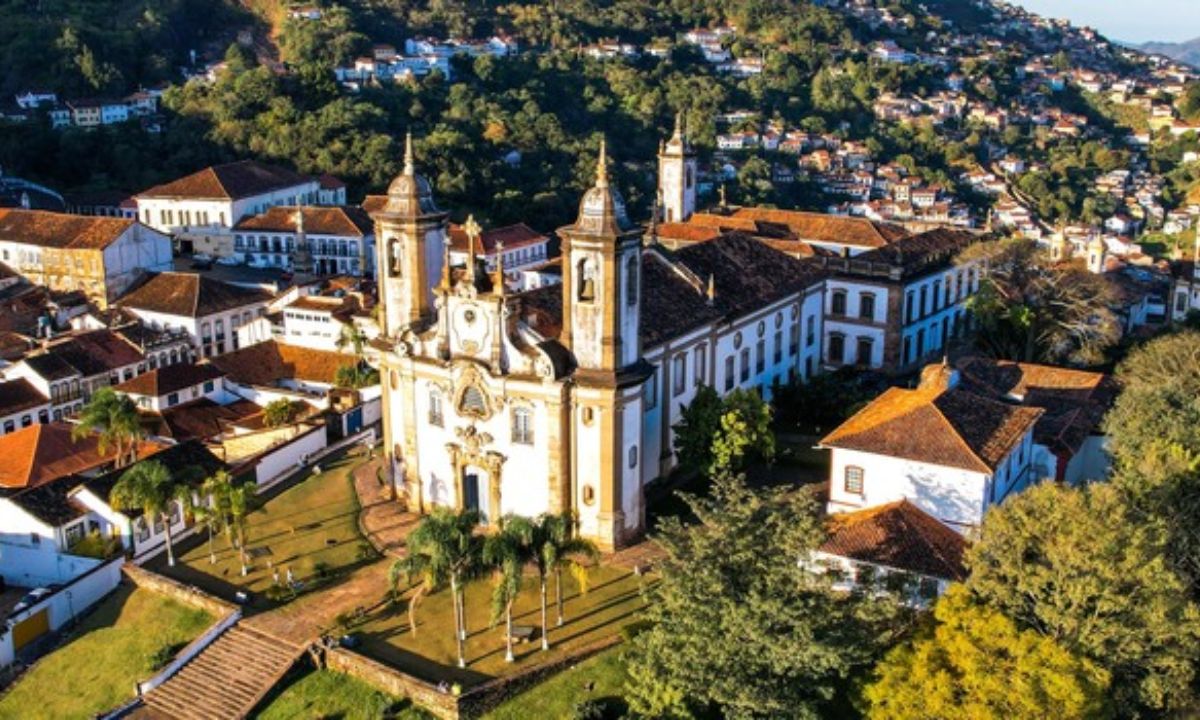 Igreja em Ouro Preto vista de cima. Ao redor, casas e uma área verde