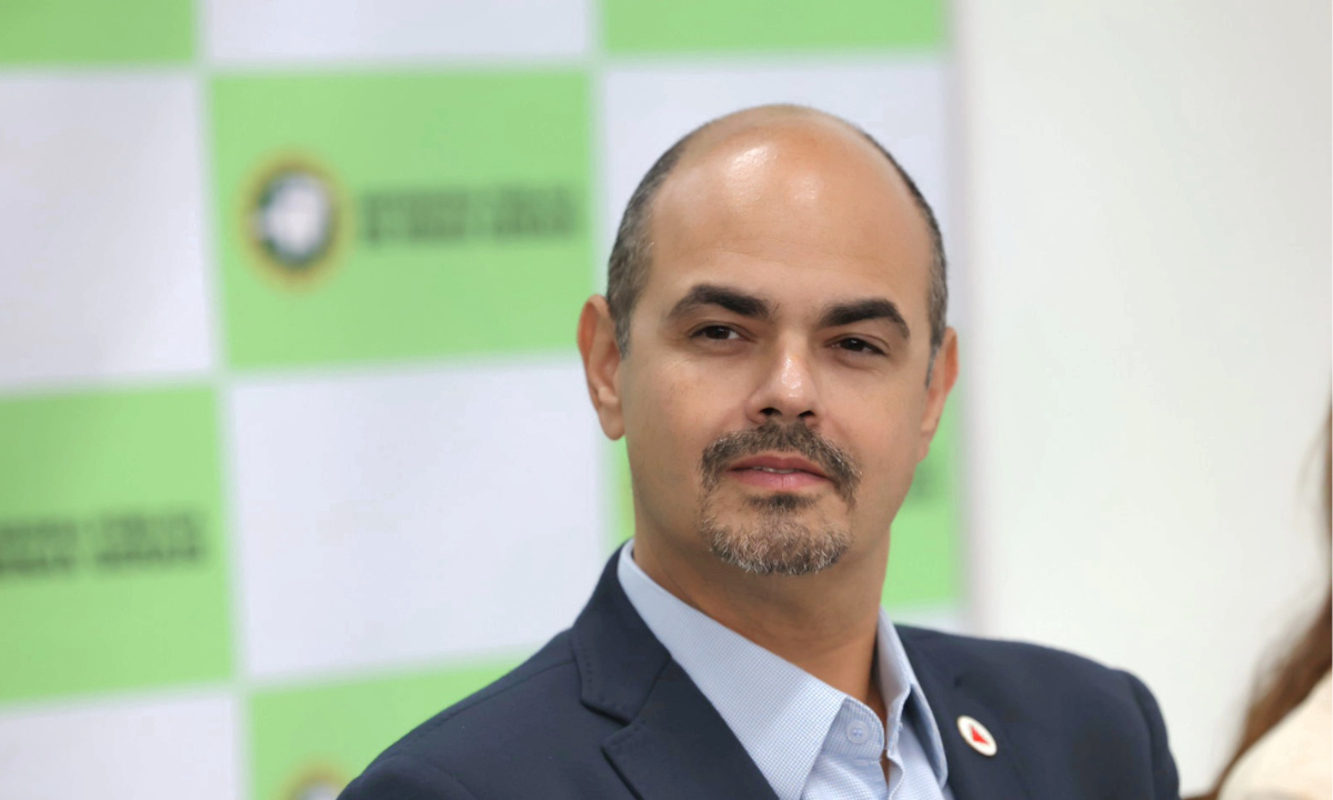 O governador Mateus Simões (PSD) em primeiro plano, com backdrop da Defensoria Pública de Minas Gerais ao fundo.