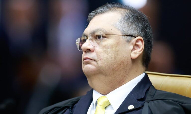 Flávio Dino de toga e gravata amarela, de perfil, no STF
