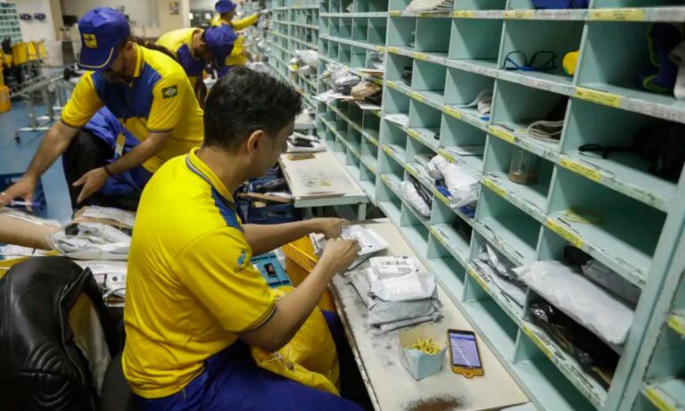 Trabalhadores dos Correios em área interna da agência